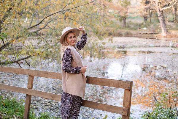 Atractiva joven sonriente mujer en ropa de moda y sombrero en el parque de otoño en otoño —  Fotos de Stock