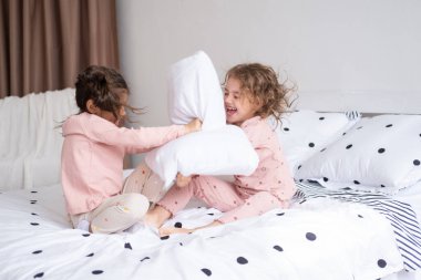 İki çocuk pijamalı, yastık savaşı yapan modern, parlak bir dairede..
