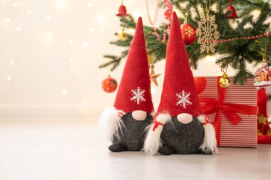 Noel ağacının altında ışık saçan iki cüce ve hediye kutusu..