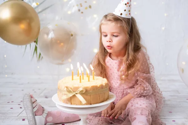 Linda niña soplando velas en pastel de cumpleaños y celebrando cumpleaños —  Fotos de Stock