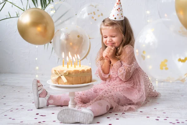 Мила маленька дівчинка дме свічки на день народження торт і святкує день народження — стокове фото