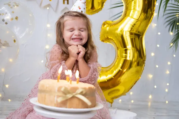 Küçük tatlı kız doğum günü pastasında mum üflüyor ve doğum gününü kutluyor. — Stok fotoğraf