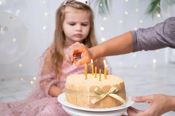 Máma světla svíčky na narozeninový dort roztomilé holčička — Stock fotografie