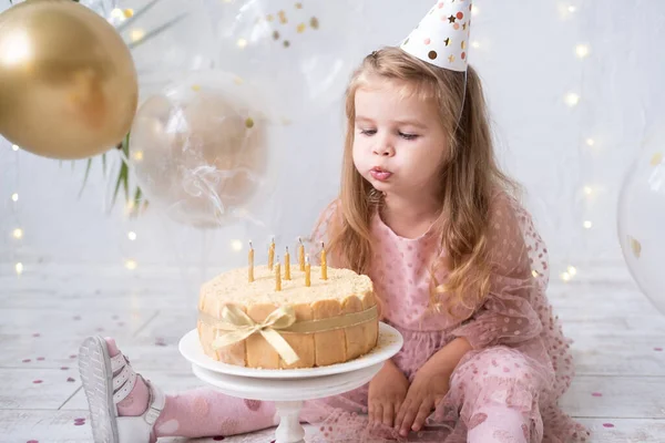 Χαριτωμένο κοριτσάκι φυσάει κεριά στην τούρτα γενεθλίων και γιορτάζει τα γενέθλια — Φωτογραφία Αρχείου