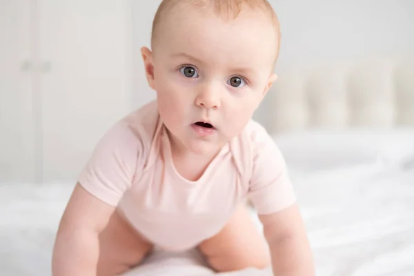 Retrato de bebê menina 10 meses em luz rosa bodysuit na cama branca — Fotografia de Stock