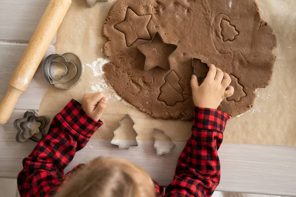 Kleines Mädchen im roten Pyjama kocht festliche Lebkuchen in der weihnachtlich dekorierten Küche. Weihnachtsplätzchen — Stockfoto