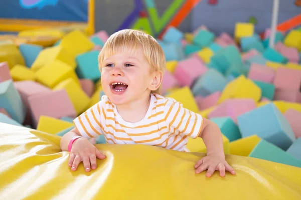 Cute smiling child boy plays with soft cubes in the dry pool in play center — Zdjęcie stockowe