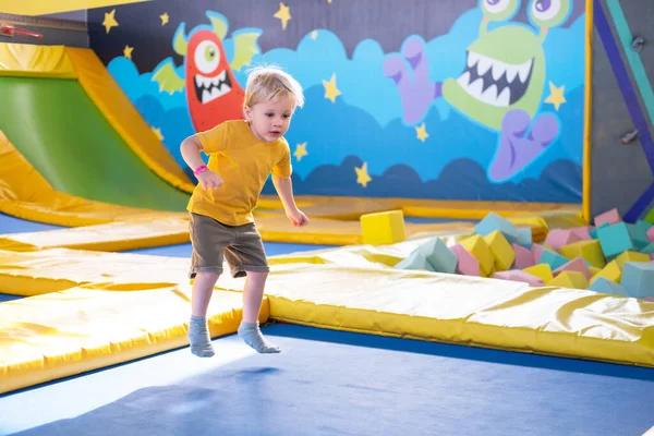 Lindo niño rubio salta en un parque de trampolín, actividad de los niños Fotos De Stock