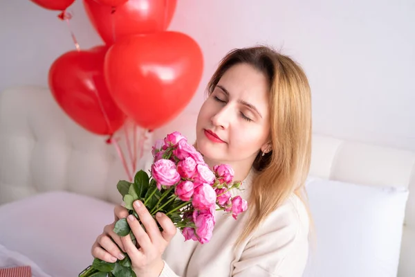 Mulheres bonitas segurando buquê de rosas cor-de-rosa na cama celebrando o dia dos namorados — Fotografia de Stock