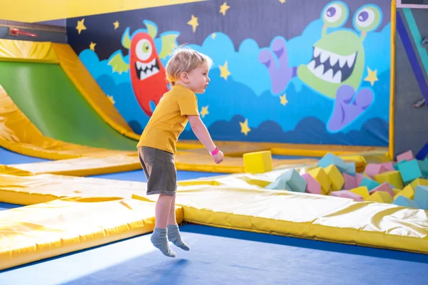 Netter blonder kleiner Junge springt im Trampolinpark, Kinderaktivität — Stockfoto