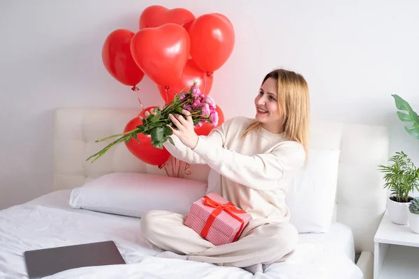 Mulheres bonitas segurando buquê de rosas cor-de-rosa na cama celebrando o dia dos namorados — Fotografia de Stock