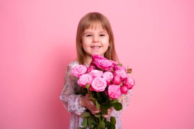 Pembe arka planda pembe gül buketi tutan güzel kız çocuğu.