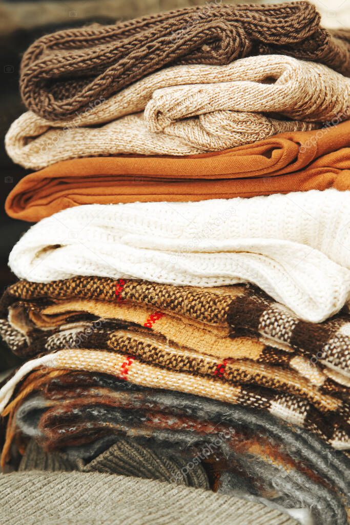 Stack of warm sweaters and blankets. Factory textiles. Autumn composition