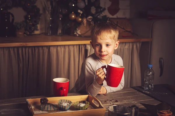 その少年は台所でマフィンとお茶を飲んでいる クリスマスの装飾 家族の伝統 クリスマスの食べ物 休日の前夜 — ストック写真