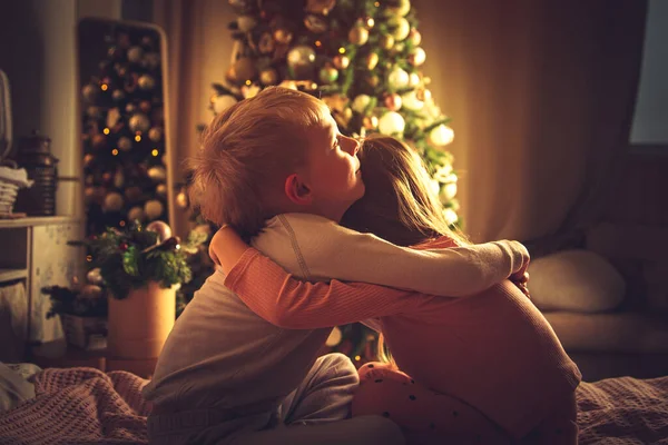 Los Niños Sientan Abrazados Cama Miran Árbol Navidad Decoraciones Navidad — Foto de Stock