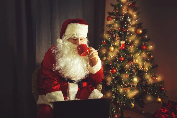 Autentyczny Święty Mikołaj Pracuje Laptopie Pije Gorącą Czekoladę Wnętrze Oczekiwaniu — Zdjęcie stockowe