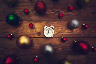 Alarm saati gece yarısını ve ahşap arka planda çok renkli Noel toplarını gösteriyor. Karanlık Noel geçmişi. 