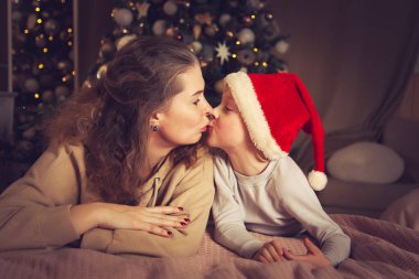 Anne ve oğlu yatakta yatıyor. Noel süsleri, bayramı bekliyor..