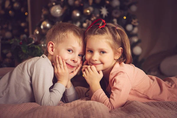 Crianças Deitam Cama Olham Para Câmara Decorações Natal Esperando Feriado — Fotografia de Stock