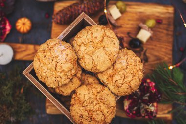 Tahta masadaki kurabiyeler. Taze çiçekler, mumlar, yosunlar ve çelenklerle süslenmiş. Eko tarzı yemek masası. Seçici odak.