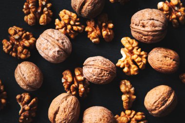 Siyah arka planda tam ve soyulmuş ceviz. Yakın çekim, düz yatış, üst manzara. Gıda arka planı, seçici odak. 