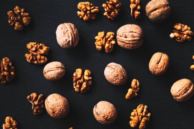 Siyah arka planda tam ve soyulmuş ceviz. Yakın çekim, düz yatış, üst manzara. Gıda arka planı, seçici odak. 