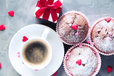 Bir fincan kahve, çikolatalı kek ve gri arka planda hediye. Romantik bir sabah, doğum günü ya da sevgililer günü konsepti. 