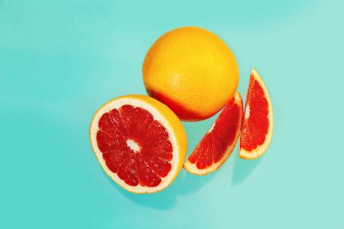 Açık mavi arka planda tam ve dilimlenmiş sulu greyfurtlar. Gıda arkaplanı. 