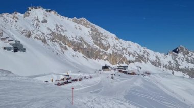 Alman Alpleri 'ndeki kayak merkezinin panoraması. Güneşli bir kış gününde kayak pistinde kayakçılar.
