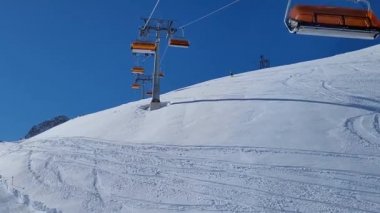 Alman Alplerinde bir kayak merkezinde kayak asansörü. Güneşli bir kış gününde kayak pistinde kayakçılar.