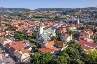 Güney Slovakya 'da Krupina' nın küçük ortaçağ kasabasının modern blok evleri ile eski binalar arasındaki ortaçağ şehir duvarının izleriyle hava panoramik manzarası açık hava sinemasına dönüştü.