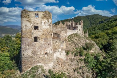 Aerial view of under restoration medieval Sasovsky castle above the Hron (Garam) river in Slovakia with circular gate tower, ruined gothic palace blue cloudy sky near Ziar nad Hronom