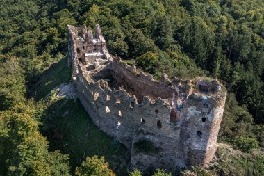 Aerial view of under restoration medieval Sasovsky castle above the Hron (Garam) river in Slovakia with circular gate tower, ruined gothic palace blue cloudy sky near Ziar nad Hronom