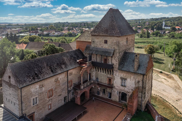 Вид с воздуха на средневековый готический замок Симонторния, защищающий крест на реке Сио в уезде Толна Венгрия с восстановленным донжоном, дворцом, кирпичными стенами голубое облачное небо