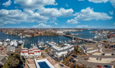 Annapolis limanının panorama limanında marinaya yanaşmış lüks yelkenliler, dereyi geçen asma köprü, Maryland devlet binası ve deniz okulu, lüks deniz kenli evler.