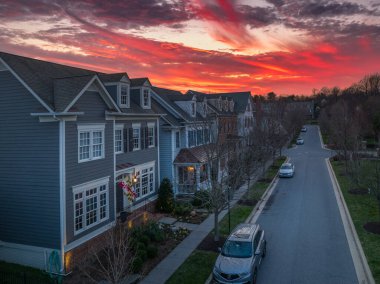 Maryland 'de renkli ateş gökyüzü olan yeni bir gayrımenkul inşaatında birbirlerine yakın yeni bir mahalle caddesinde inşa edilen lüks Amerikan aile evleri günbatımı manzarası.