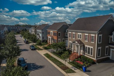 Modern üst sınıf banliyö Amerikan gayrimenkul gelişim topluluğunun havadan görünüşü, büyük, tek aile evleri vinil ve tuğla kaplamalı portico girişe kadar uzanan bulutlu mavi gökyüzüne çıkıyor.