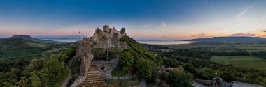 Macaristan 'ın Balaton Gölü yakınlarındaki Szigliget kalesinin hava manzarası güneş batmadan saatler önce kapandıktan sonra