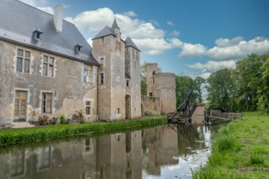 Fransa 'daki tarihi anıt Bannegon şatosunun su dolu hendeğin üzerinde ahşap bir köprü, heybetli bir kale, asma köprü ve trapezoidal güçlendirilmiş bir muhafaza manzarası