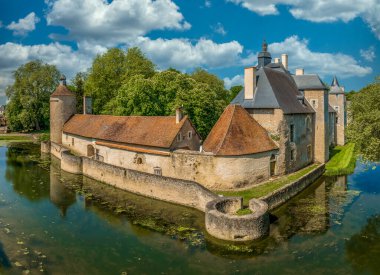 Fransa 'daki tarihi anıt Bannegon şatosunun su dolu hendeğin üzerinde ahşap bir köprü, heybetli bir kale, asma köprü ve trapezoidal güçlendirilmiş bir muhafaza manzarası
