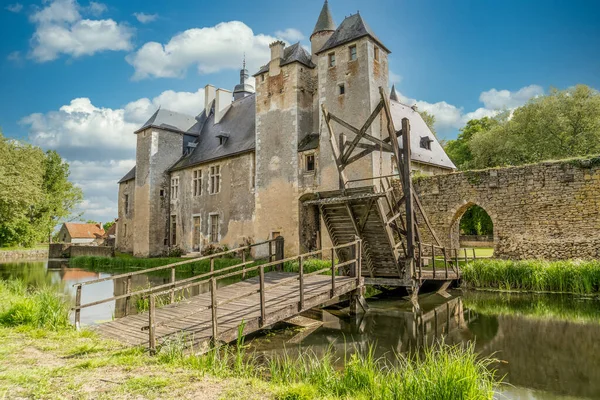 Fransa 'daki tarihi anıt Bannegon şatosunun su dolu hendeğin üzerinde ahşap bir köprü, heybetli bir kale, asma köprü ve trapezoidal güçlendirilmiş bir muhafaza manzarası