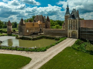 Fransa Allier 'deki Chateau de la Cour-en-Chapeau' nun havadan görünüşü. Kırmızı tuğlalardan, saraydan, kulelerden ve hendekten oluşan siyah elmas şekilli tuğlalarla inşa edilmiş.