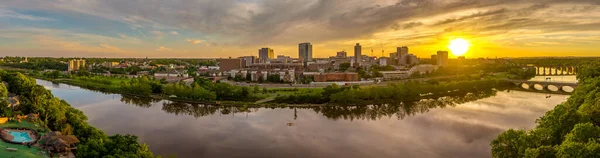 New Brunswick şehir merkezinin ve Rutgers Üniversitesi 'nin gökyüzü manzarası. Güneş yüksek binaların arkasında batıyor ve Raritan Nehri' ni yansıtıyor.