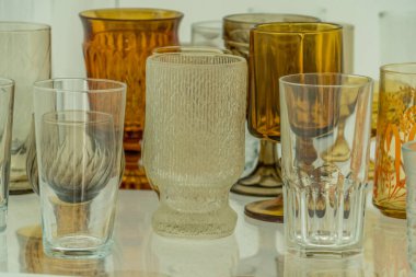 Assortment of various shapes and size yellow cups and glasses on a shelf