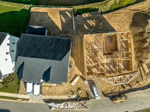 Aerial top down view of newly built luxury single family house with roof and house wooden frame under construction in a real estate development