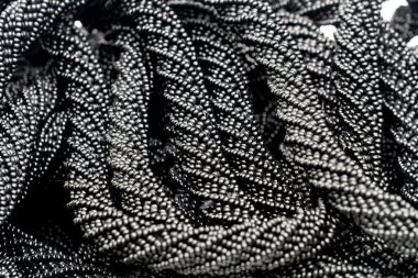 Close up view of coiled stacked rope made of glossy black beads