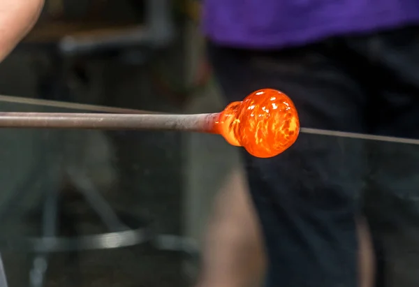 Glowing orange molten glass on an iron rod waiting to be formed