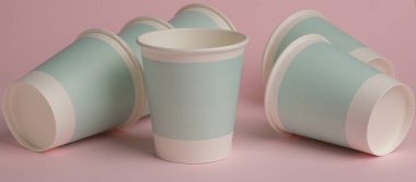 Pembe arka planda tek kullanımlık kağıt bardaklar