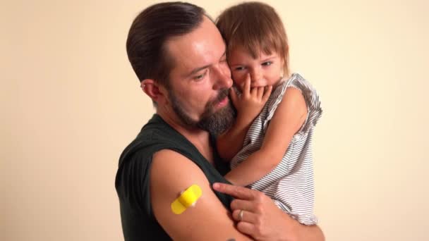 Otec s obvazem na paži po získání imunitní vakcíny drží svou dceru — Stock video