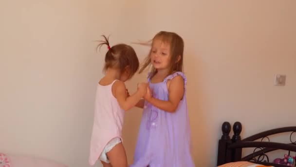 Дві сестри-малюки стрибають на ліжку — стокове відео